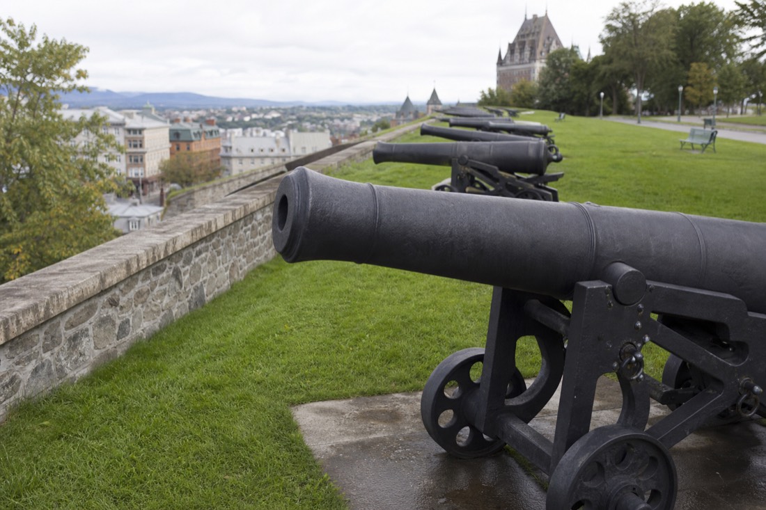 Walker on the grassy rampart walkway of Quebec City's fortifications with cannons in the foreground
