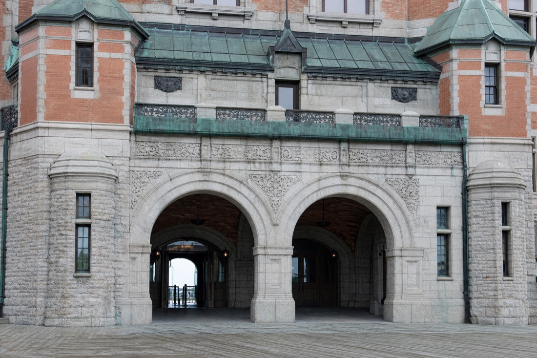 Grand entrance doors of the Château Frontenac with visitors walking through under stone archways