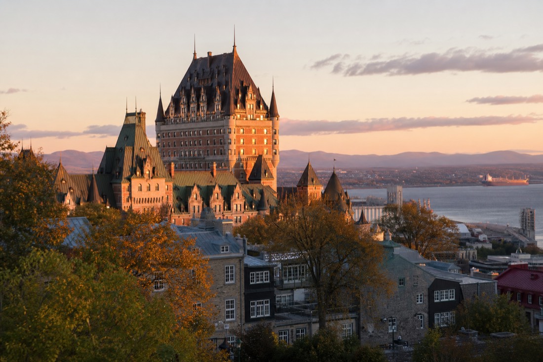 Château Frontenac photographed at golden hour from a raised terrace viewpoint with the St. Lawrence River behind