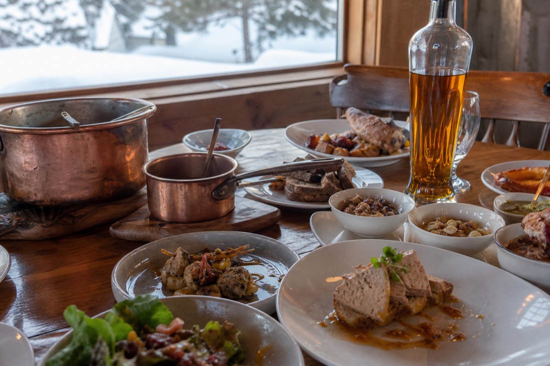 Foie gras and maple dishes crowding a wooden sugar shack table in rural Quebec