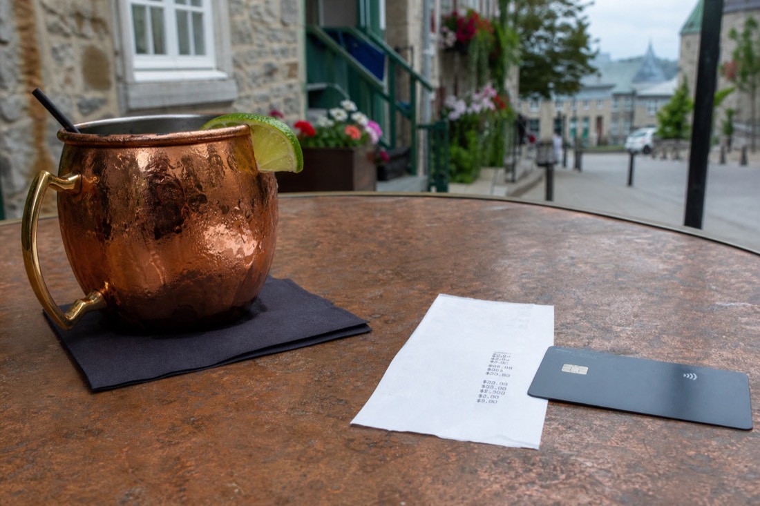 Cafe bill in Canadian dollars beside a credit card on a bistro table in Old Quebec