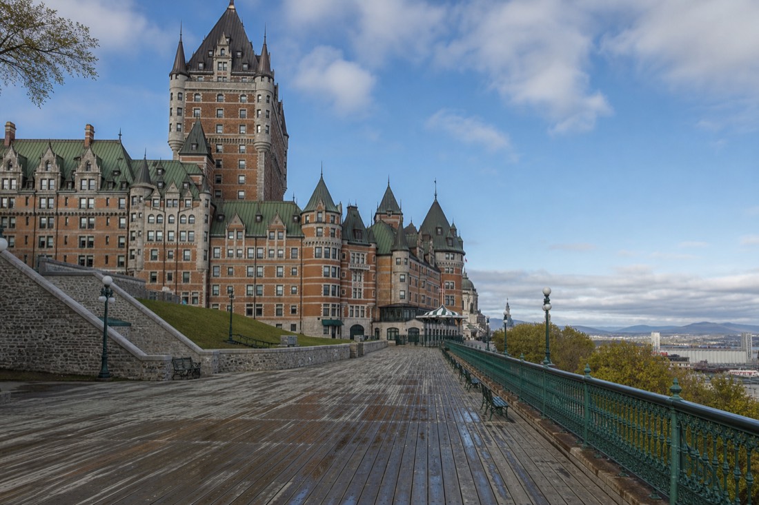 Visitors strolling the Dufferin Terrace boardwalk beside the Château Frontenac above the St. Lawrence