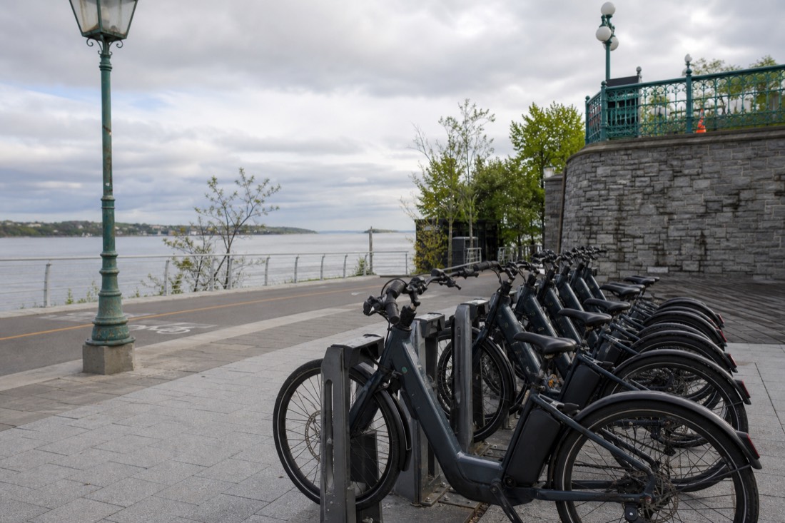 Electric bikes lined up for rental near a bike path along the St. Lawrence River in Quebec City