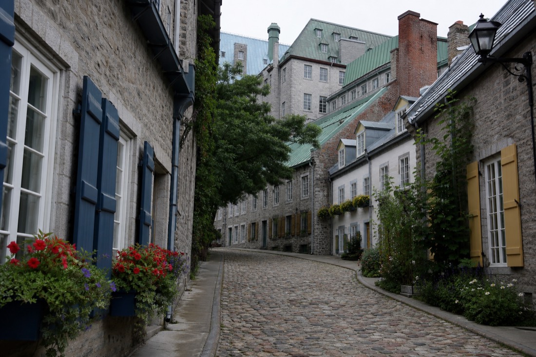 Quiet cobblestone lane in Old Quebec with stone facades and flower boxes, no vehicles in sight