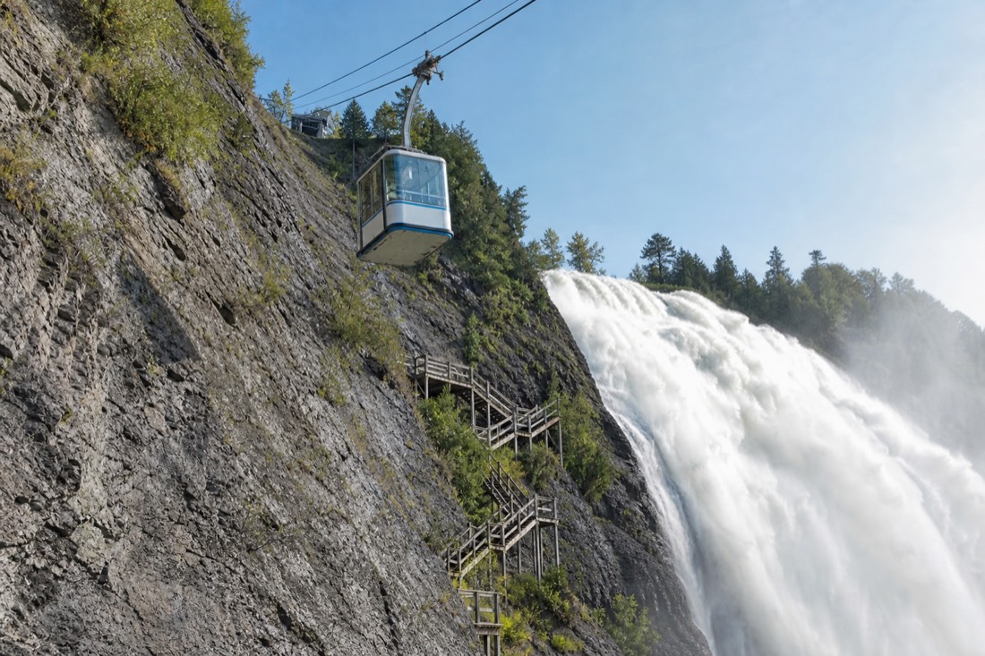 Montmorency Falls cable car cabin rising along the cliff with the wooden staircase zigzagging beside the falls