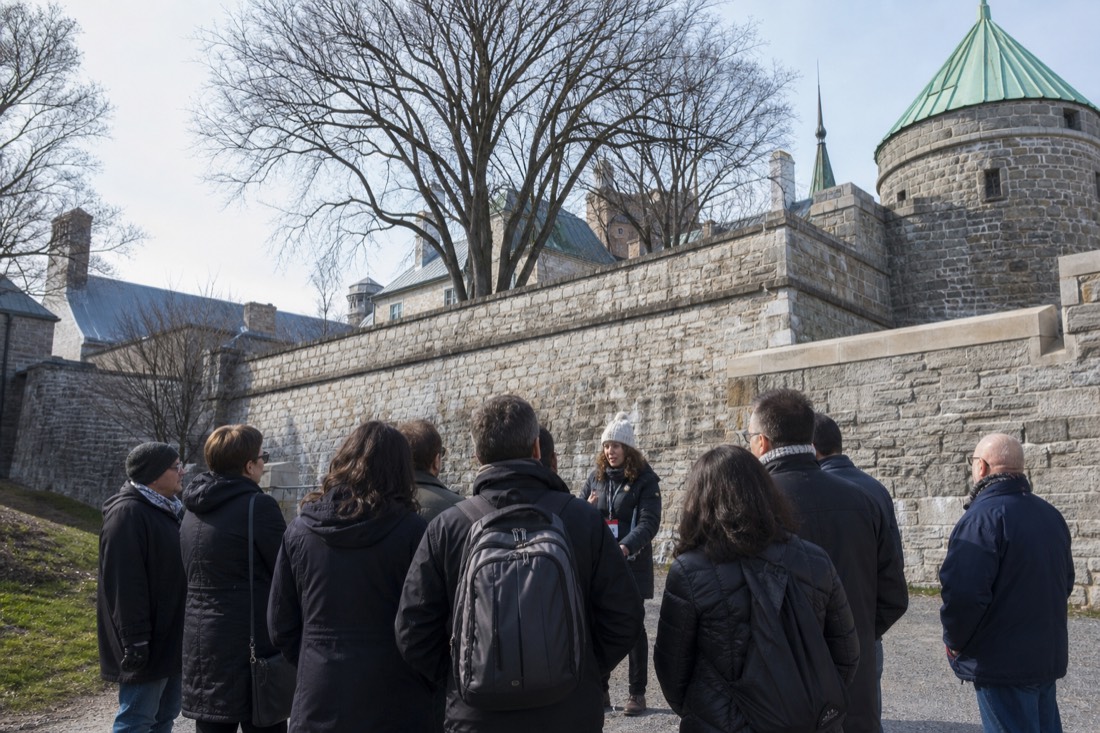 Small guided walking tour group listening to a guide beneath the walls of Old Quebec