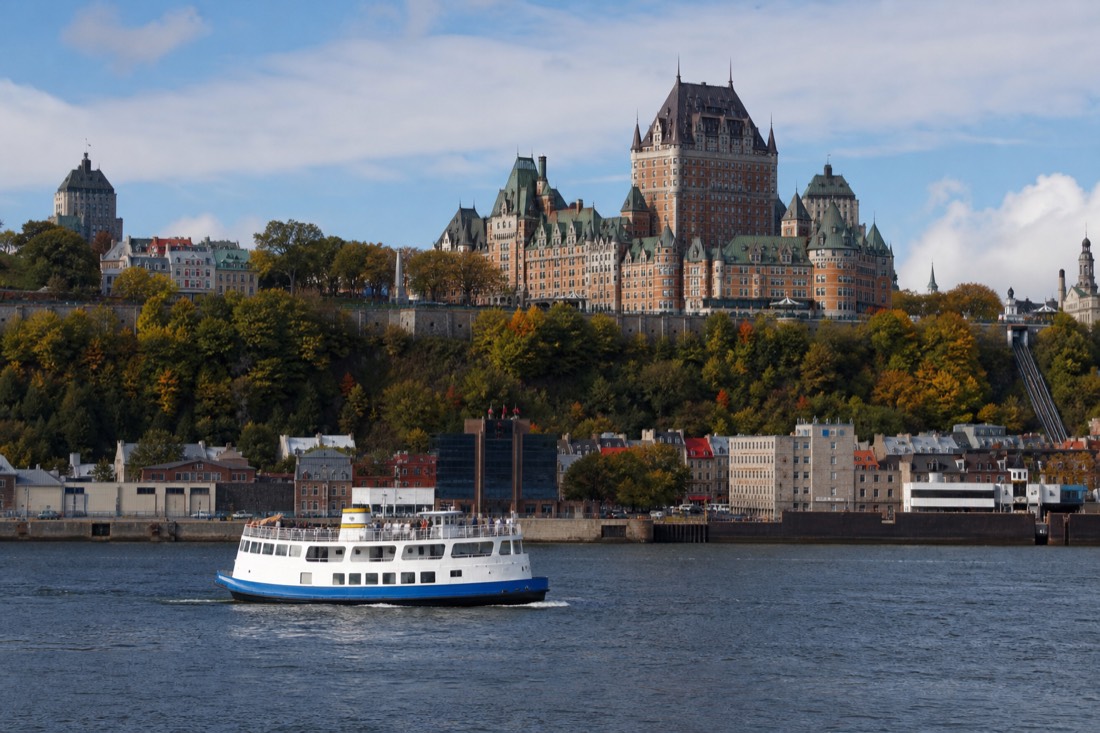 Sightseeing boat on the St. Lawrence River passing below the cliffs and skyline of Quebec City