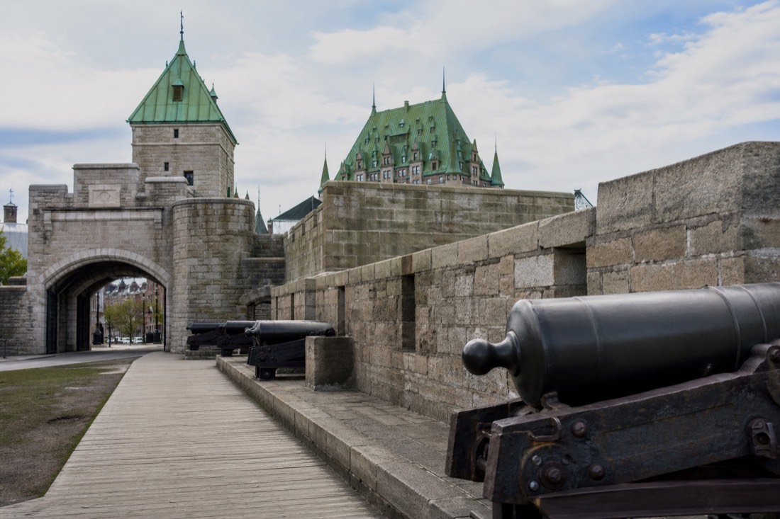 Stone ramparts and a city gate of the Old Quebec fortification walls with cannons along the walkway